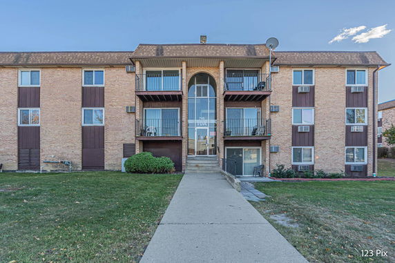 Front view of a multi-story residential building with balconies and brick facade.