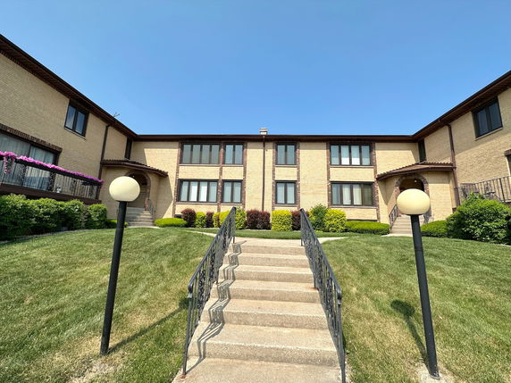 Front view of a two-story building with a staircase leading up to the entrance.