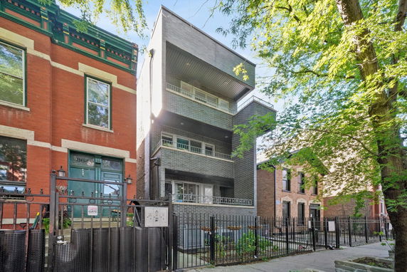 Front view of a multi-story modern house with balconies and brick exterior.