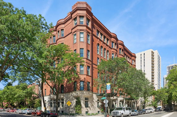 Front view of a multi-story red brick building with decorative elements and numerous windows.