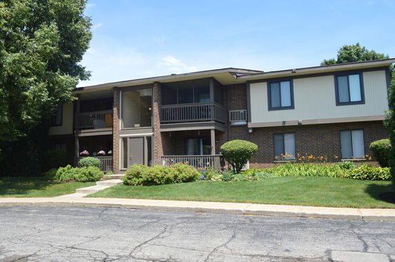 Front view of a two-story brick residential building with upper and lower level balconies.