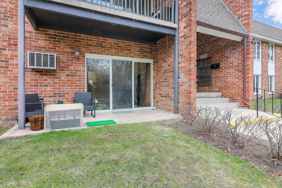 Front view of a multi-story brick apartment building with a patio area.