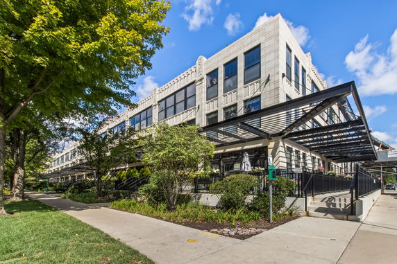 Front view of a modern multi-story building with large windows and metal awnings.