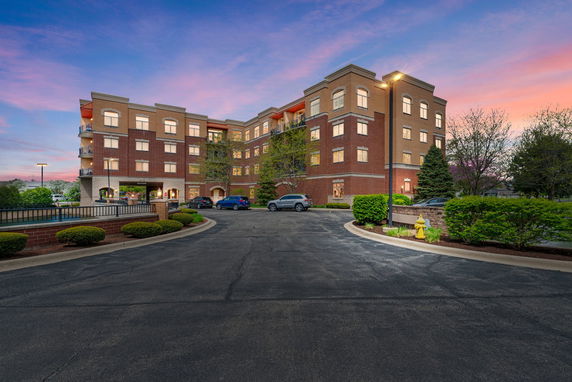 Front view of a multi-story brick building with balconies and illuminated windows.