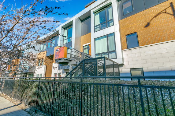 Front view of a modern multi-story building with large windows and a metal fence.