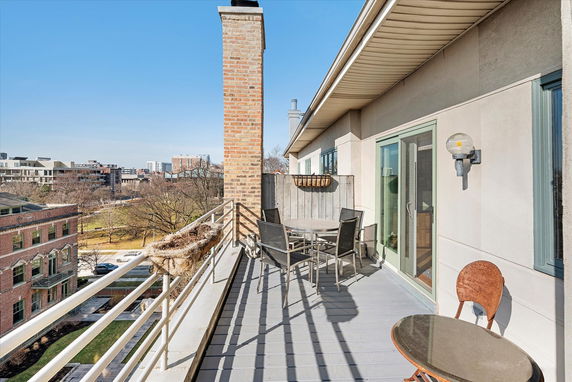 Building balcony with outdoor seating, overlooking urban surroundings.