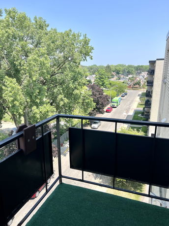 View from a balcony of a residential area with trees and a street visible below.