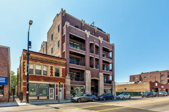 Front view of a multi-story brick building with balconies and large windows.