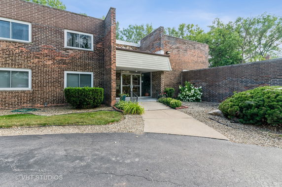 Front view of a brick building with multiple windows and a small entrance canopy.