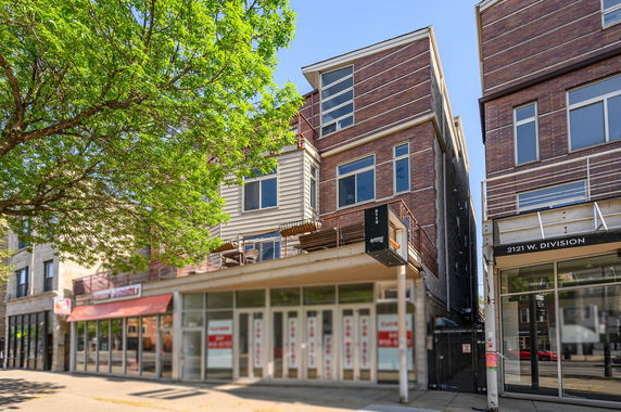 Front view of a multi-story commercial and residential building with large windows and balconies.