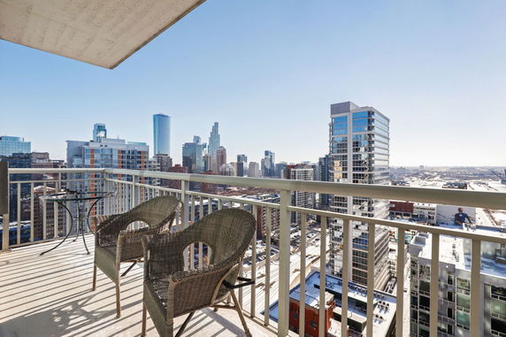 Panoramic view of cityscape from a balcony with chairs and table.