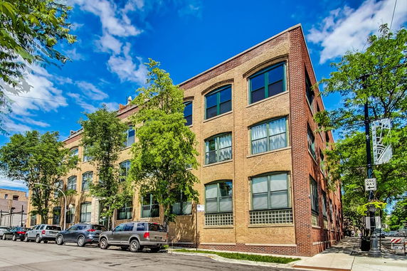 Front view of a three-story brick building with large windows.