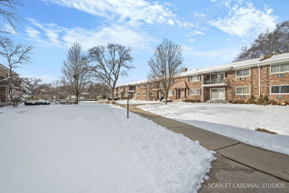 Front view of a brick apartment building with two stories in a snowy setting.