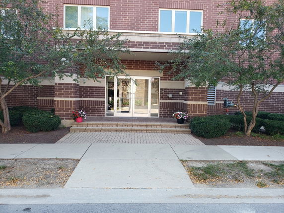 Front view of a building with brick facade and glass entrance doors.