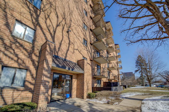 Front view of a multi-story brick apartment building with balconies.