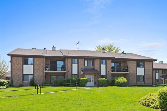 Front view of a multi-story brick apartment building with balconies.