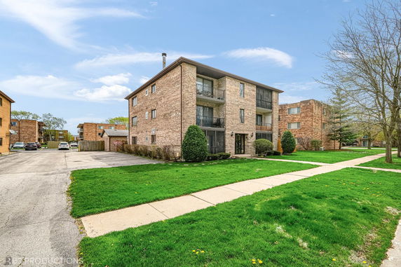 Front view of a three-story brick apartment building with balconies.