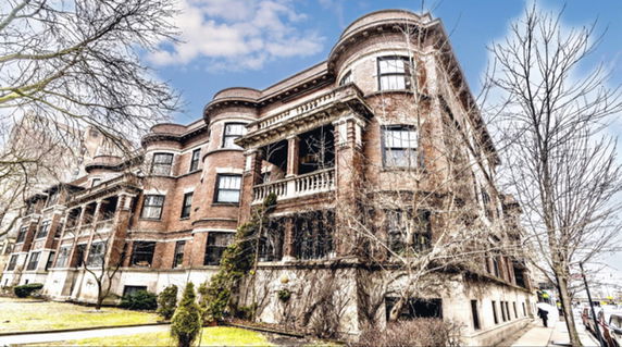 Front view of a large, historic brick building with multiple stories and intricate architectural details.