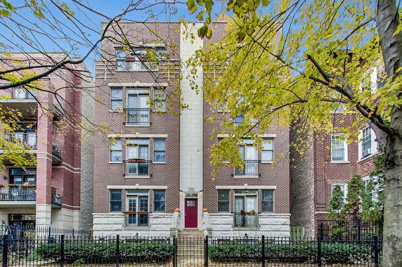 Front view of a multi-story brick apartment building with a central entrance.