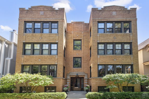 Front view of a multi-story brick building with large windows.