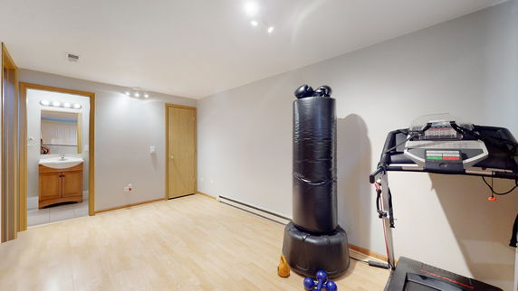 Room with exercise equipment including a treadmill and punching bag, adjacent to a bathroom.