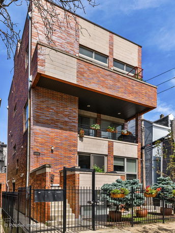 Front view of a modern multi-story building with a brick facade and balconies.