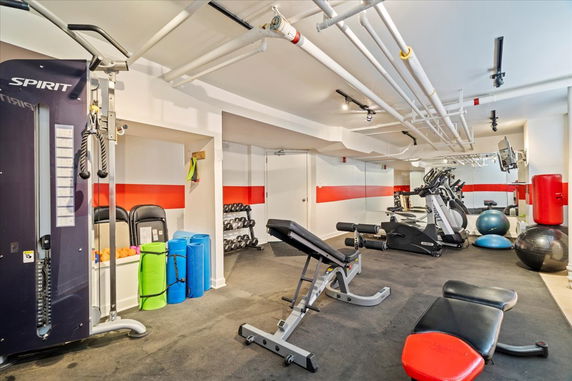 Indoor gym area equipped with exercise machines, weights, and workout mats.