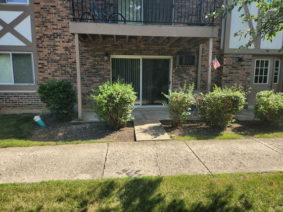 Front view of a brick building with a small patio area and balcony.