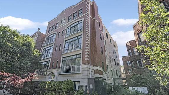Front view of a multi-story brick building with large windows and balconies.