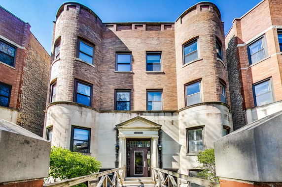 Front view of a three-story building with curved brick exterior and a central entrance.