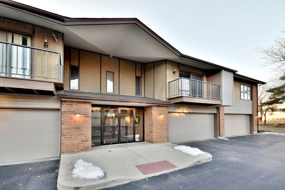 Front view of a multi-story building with garages and balconies.