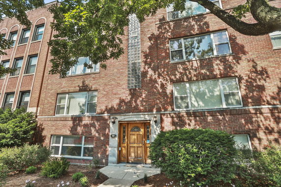Front view of a multi-story brick building with large windows.