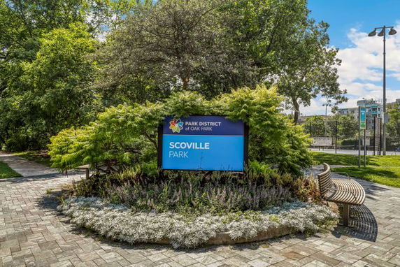 Sign for Scoville Park surrounded by plants and trees.