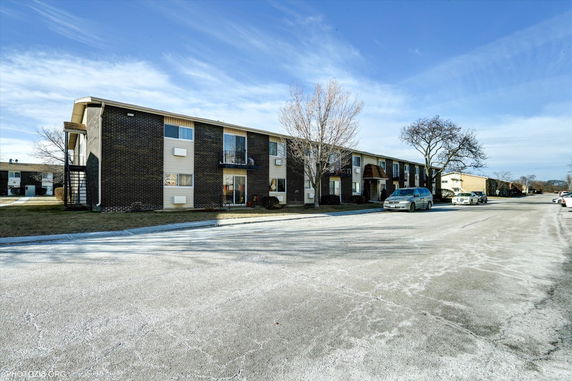 Front view of a two-story residential building with a flat roof and multiple balconies.