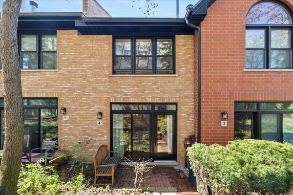 Front view of a two-story brick townhouse with multiple windows and a small patio area.