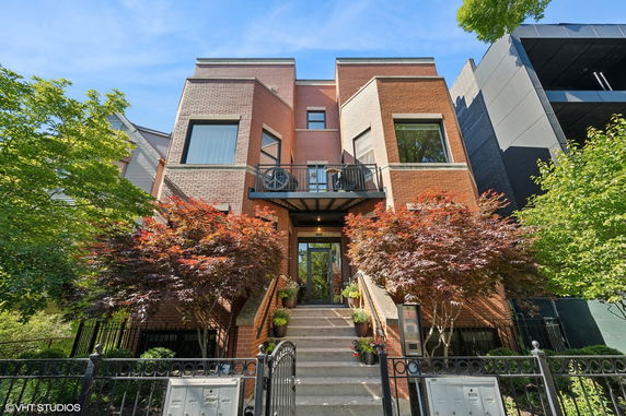 Front view of a multi-story brick building with a central entrance and a balcony.