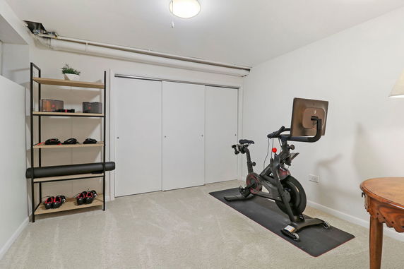 Room with exercise bike and storage shelves.