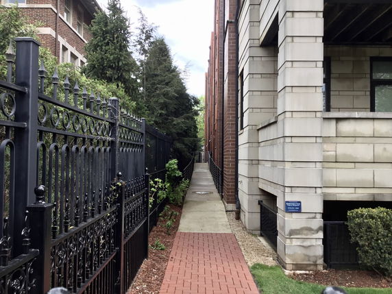 Side view of a brick and stone building with a black metal fence.