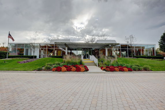 Front view of a modern single-story building with large glass windows and an entrance pathway.
