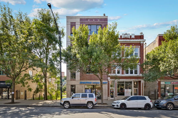 Front view of a multi-story brick building with ground-floor businesses.