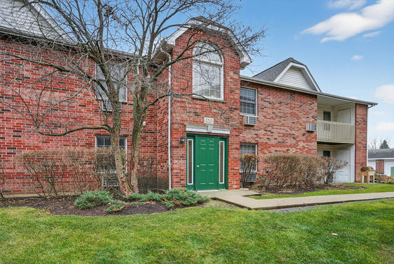 Front view of a brick residential building with a green door and upper balcony.