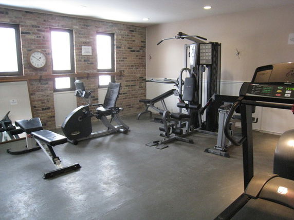Room with gym equipment including a treadmill, exercise bike, and weight machine.