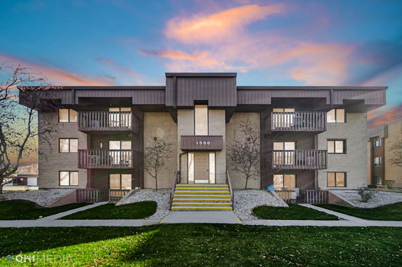 Front view of a multi-story building with balconies and a central entrance.