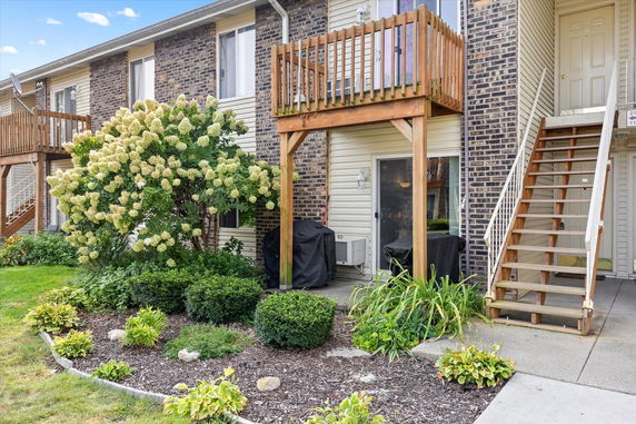 Front view of a two-story building entrance with a wooden staircase and balcony.