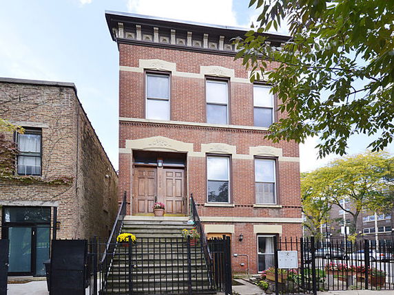 Front view of a two-story brick building with a central staircase leading to the entrance.