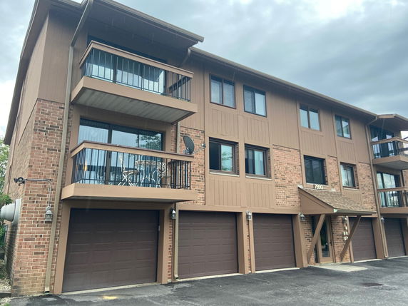 Front view of a multi-story building with balconies and garage doors.