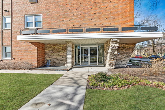 Front view of a brick and stone building entrance with glass doors.