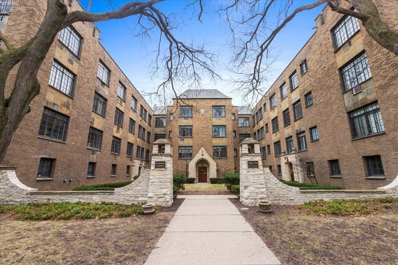 Front view of a multi-story brick apartment building with an arched entrance.