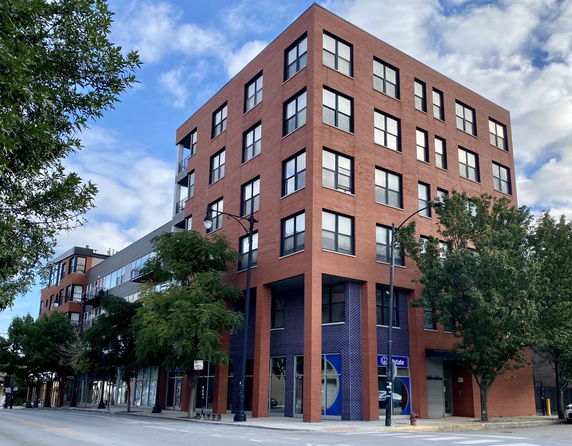 Front view of a multi-story brick building on a city street corner.