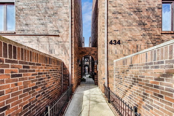 Narrow passage between two brick buildings with an arched gate.